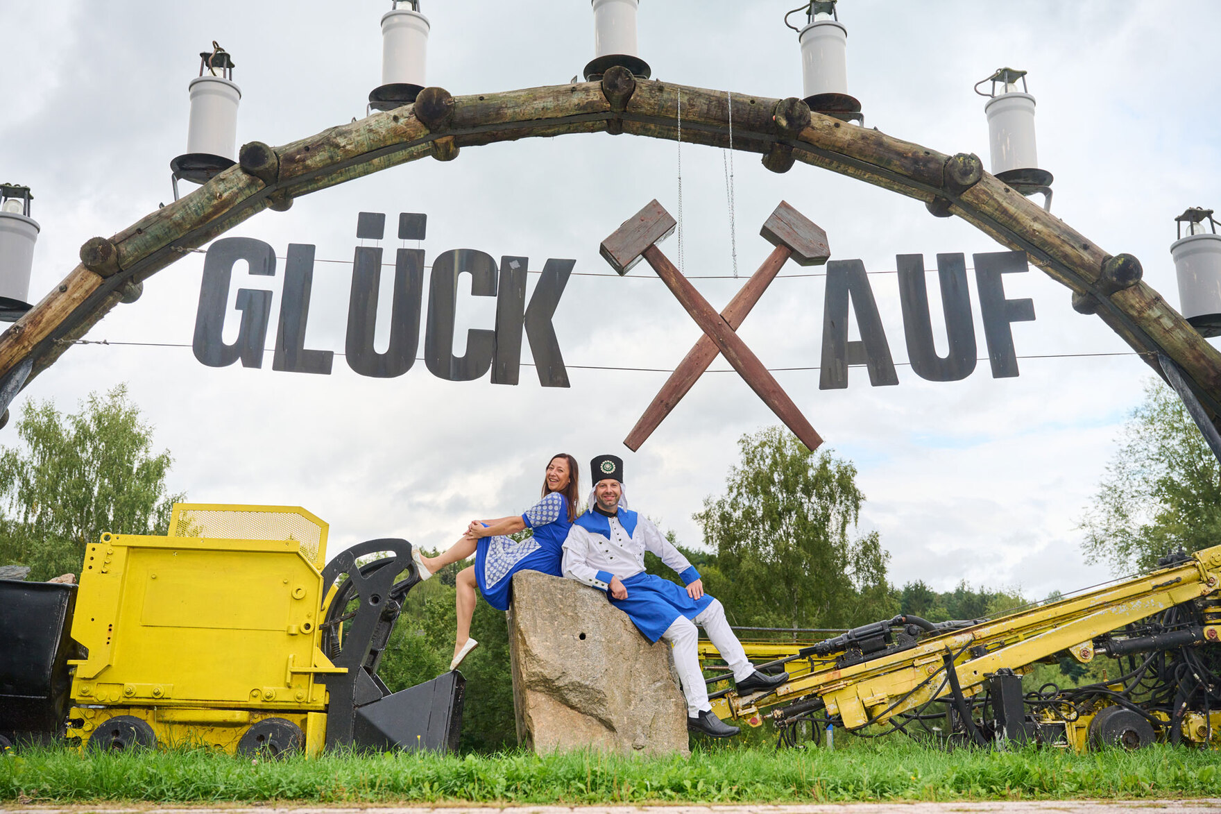 Ein Mann und eine Frau sitzen unter einem Schwibbogen, auf dem »Glück auf« steht.