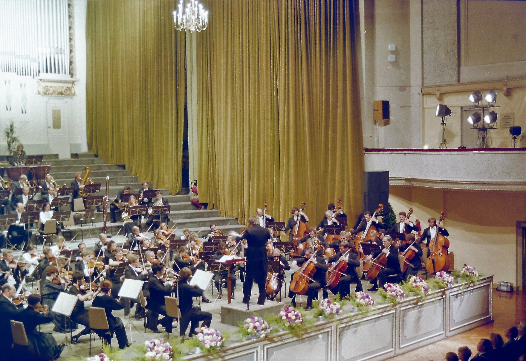 Ein Orchester in einem Konzertsaal spielt unter der Leitung eines Dirigenten