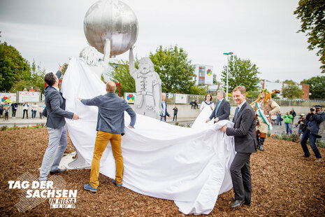 Männer enthüllen eine Statue