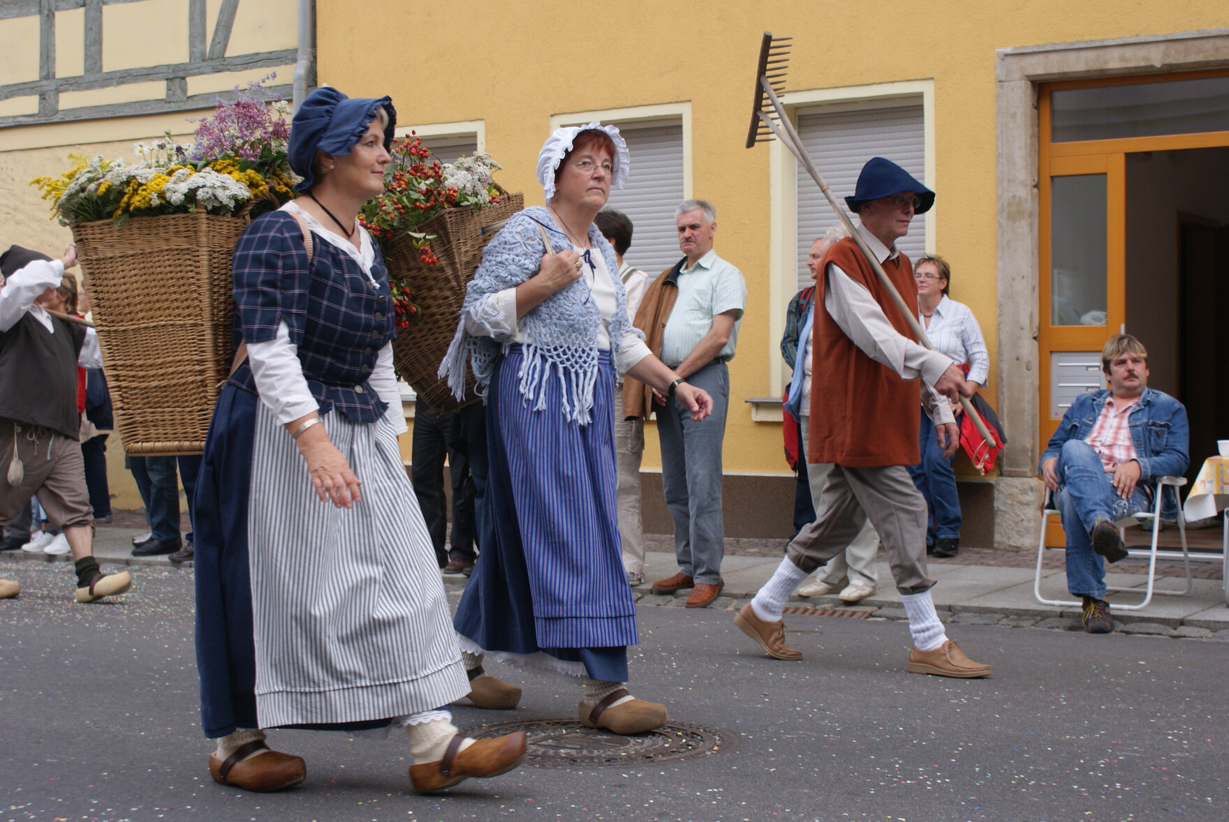Frauen und Männer in historischer Arbeitskleidung mit Körben und Rechen beim Umzug