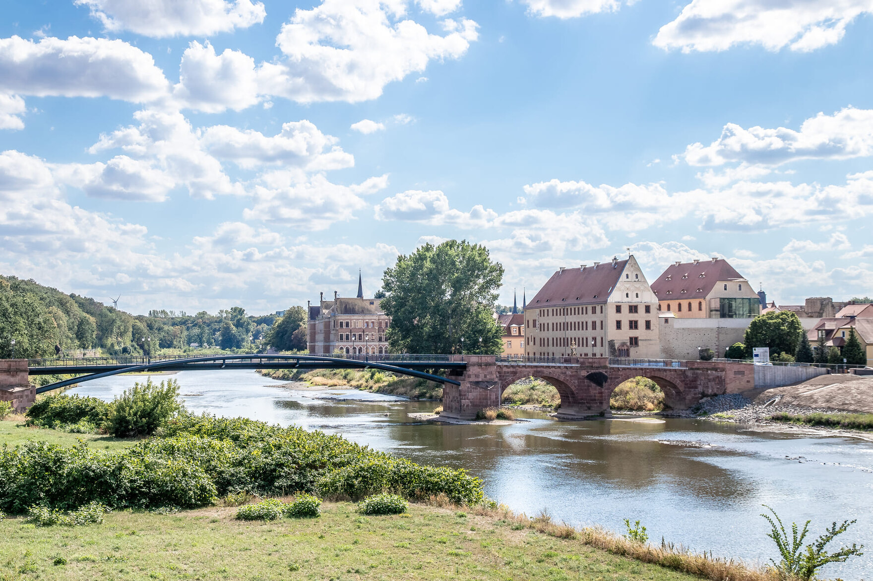 Historische Brücke mit angrenzenden Gebäuden am Fluss unter blauem Himmel