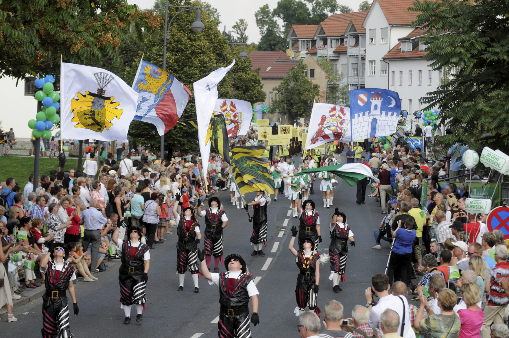 Festumzug mit Fahnenschwingern und Zuschauern auf Straße