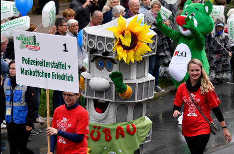 Foto vom Festumzug mit dem Maskottchen.